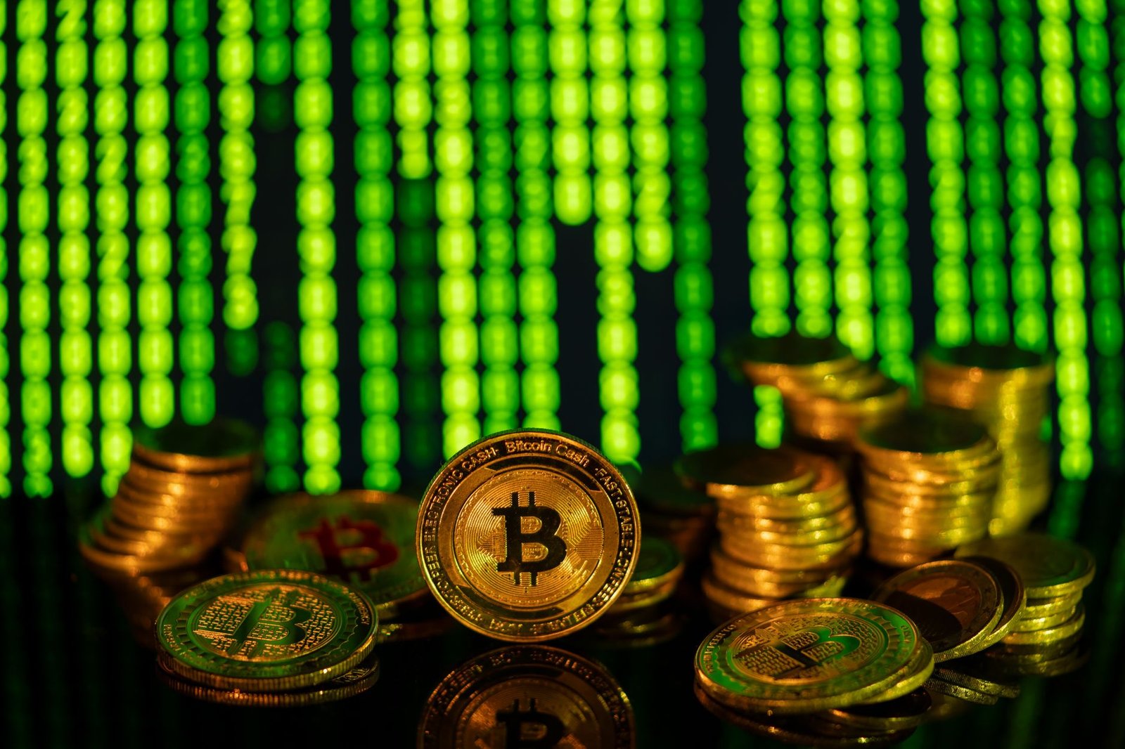 Stacks of golden bitcoins in front of a digital matrix, symbolizing cryptocurrency and blockchain technology.